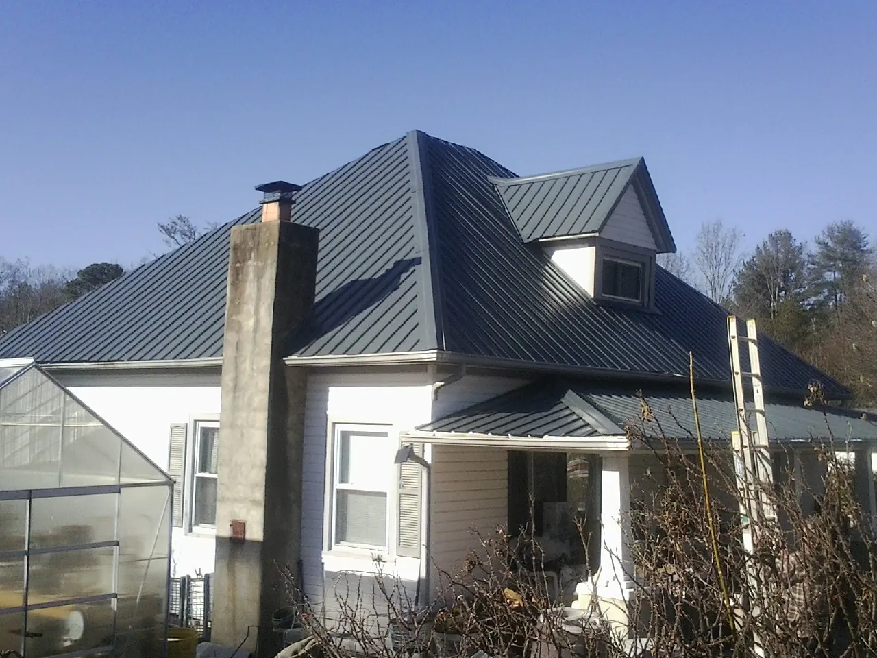Dark blue standing seam metal roof on a white farmhouse with dormer — Slate & Tile Roof Repair by Roofing Brothers in Ocean Park